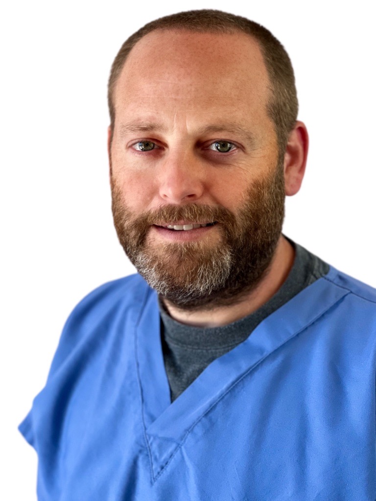 A photo of Dr. Eric Ebaugh, General Surgeon. He is wearing blue scrubs and smiling into the camera.